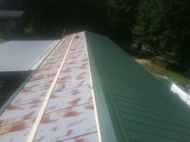 Old rusted panels beside newly installed green metal roofing — Wind Damage Roof Repair by Roofing Brothers in Pilot Point