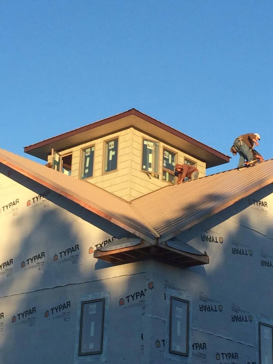 Roofers working around a rooftop cupola on a new metal roof at sunset — Roof Waterproofing in Pilot Point by Roofing Brothers